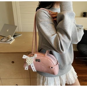 Détail du nœud en dentelle rose et du pendentif cœur en perles sur le sac à main chic