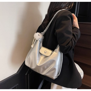Metallic silver tote bag on a model shoulder featuring a soft white plush pendant