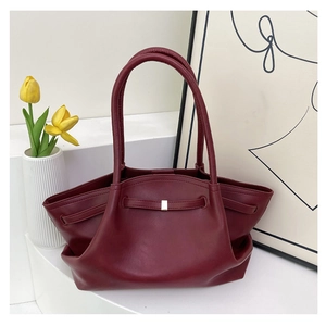 Close-up of side pleat design on deep red tote bag with minimalist metal accents
