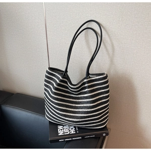 Detail of black and white striped straw tote bag showing large capacity and long handles