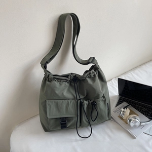 Detail of army green nylon shoulder bag with drawstring closure and utility cargo pockets