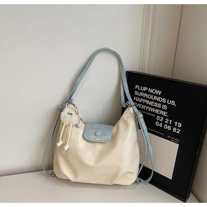 Detail of off-white leather tote bag with light blue strap and plush pendant