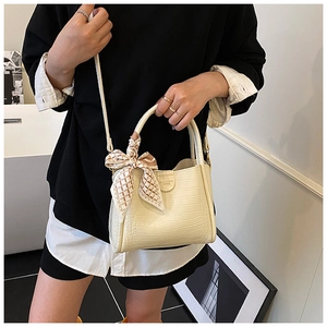 Détail du sac seau crème avec texture crocodile et nœud décoratif en ruban à carreaux