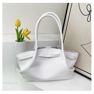Detailed close-up of a white leather tote bag with wing-shaped design and gold buckle