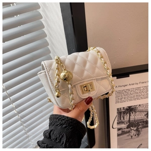 Detailed macro view of white quilted mini square bag with golden chain and ball charm