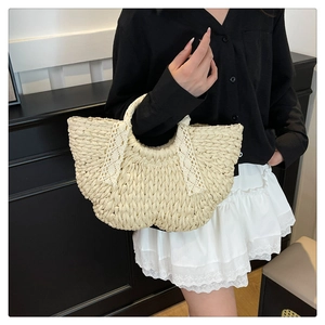 Détail d'un sac à main en paille avec des nœuds en dentelle blanche et texture tressée