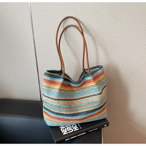 Detail of colorful rainbow striped straw tote bag with brown leather handles for beach vacation