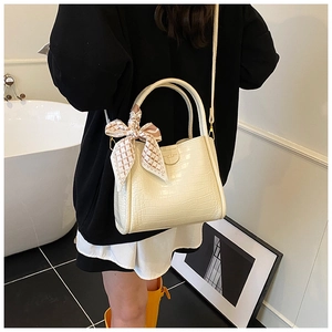 Détail du sac seau crème à motif crocodile avec foulard décoratif en soie porté