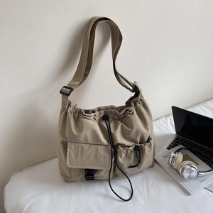 Detail of khaki waterproof nylon shoulder bag with drawstring closure and buckle pockets