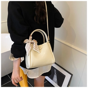 Détail du sac seau crème en cuir crocodile avec un foulard en soie décoratif