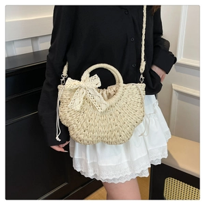 Détail du sac en paille tressée avec nœud en dentelle blanche et fermeture à cordon