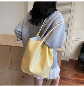 Detail view of yellow faux leather tote bag featuring a textured crocodile pattern