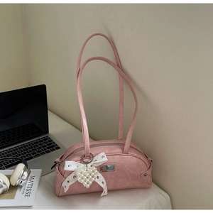Détail du sac à bandoulière rose avec breloque cœur en perle et plaque métallique