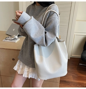 Detail of white crocodile pattern tote bag with double handles and embossed PU texture
