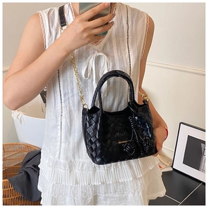 Détail d'un sac seau tressé noir avec chaîne dorée et nœud de cordon en cuir élégant