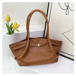 Detail view of brown tote bag with side fold structure and golden metal buckle decoration