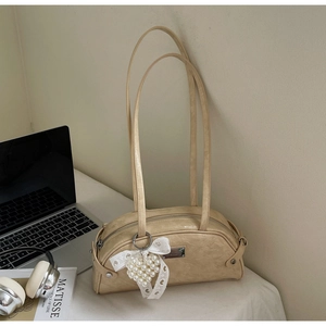 Détail du sac beige en similicuir plissé avec breloque cœur en dentelle et plaque argent