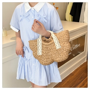 Détail d'un sac tressé main avec poignées en dentelle blanche et fermeture à cordon