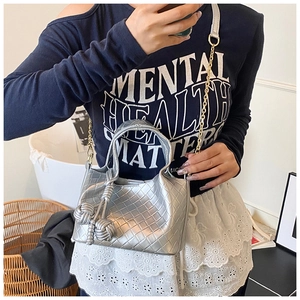 Détail du sac seau tressé argenté avec finition métallique et breloque en nœud