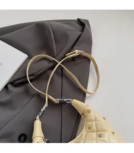 Detailed close-up of beige quilted leather shoulder bag with silver studs and strap