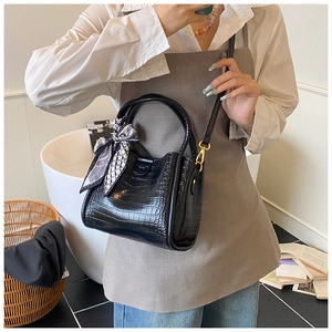 Détail du sac seau noir gaufré crocodile avec ferrures dorées et décoration en soie