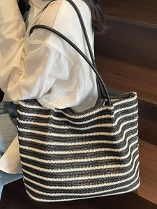 Large striped straw woven tote bag with black handles for beach vacations and daily use