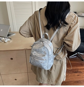 Détail d'un mini sac à dos argenté avec strass porté par un mannequin dans un bureau