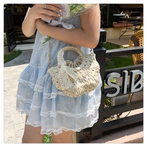 Détail du sac de plage en paille tissée beige avec nœud en dentelle et doublure intérieure