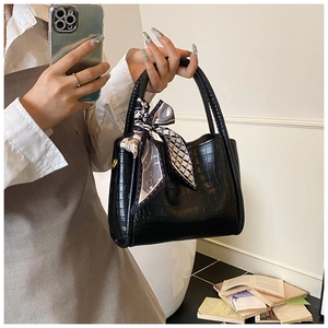 Détail du sac à main noir en cuir gaufré crocodile avec foulard en soie sur la poignée