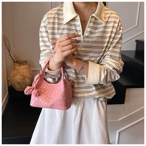 Gros plan d'un sac seau tressé rose avec poignée tressée et détail de nœud chic