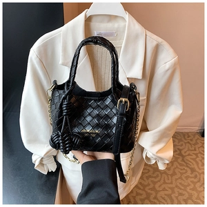 Détail du sac seau en cuir tressé noir avec bandoulière chaîne dorée et noeud