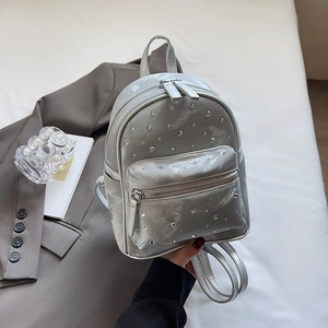 Détails d'un mini sac à dos argenté orné de strass brillants et finition métallique