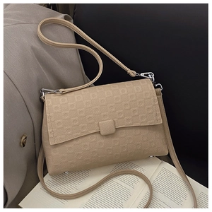Detail view of a beige textured crossbody bag with silver hardware and geometric patterns