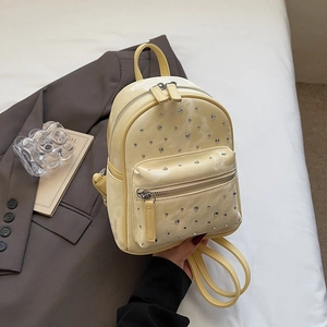 Gros plan détaillé du mini sac à dos jaune crème avec des décorations en strass brillants