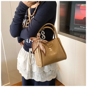 Détail du sac seau kaki à motif crocodile avec foulard décoratif sur la poignée