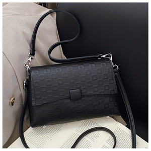 Close-up of geometric embossed texture and silver hardware on black crossbody bag