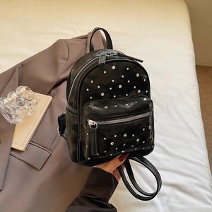 Détail d'un mini sac à dos noir en cuir PU avec clous en strass argentés et poignée supérieure