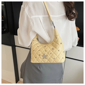 Detail of quilted cream hobo bag featuring a star-shaped diamond emblem and metal rivets