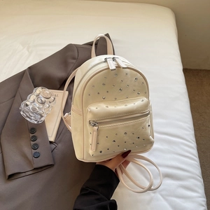 Gros plan d'un mini sac à dos crème en PU avec strass brillants et fermetures éclair argent