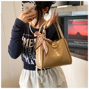 Détail du sac à main kaki à texture crocodile avec foulard en soie et tenue décontractée bleue
