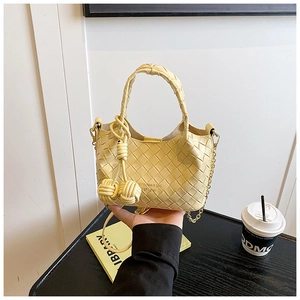 Détail du sac seau jaune tressé avec texture croisée et bandoulière en chaîne métal