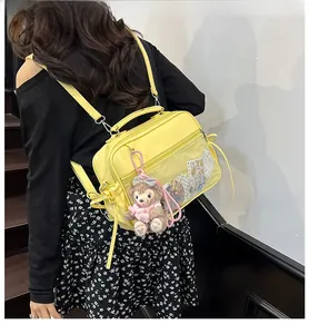 Detail view of yellow PVC crossbody bag featuring clear display pocket and plush charm