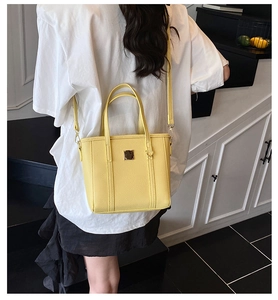 Detail of bright yellow lychee pattern tote bag with metal buckle on minimalist background
