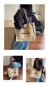 Close-up of beige canvas tote bag with brown leather handles and black letter printing