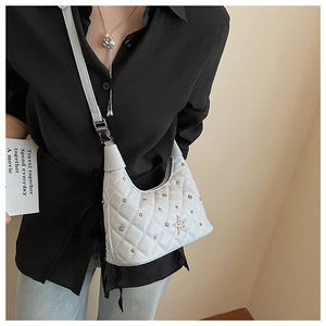 Quilted white shoulder bag with star buckle and metal studs shown on model shoulder