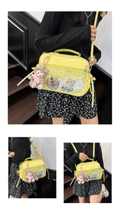 Detail view of yellow Ita bag with clear window, plush bear charm and ribbon accents