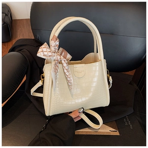 Détail du sac seau crème effet crocodile avec foulard en soie et logo sur siège cuir