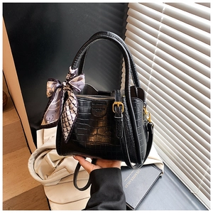 Détail d'un sac seau en cuir noir motif crocodile avec foulard en soie et boucle en métal