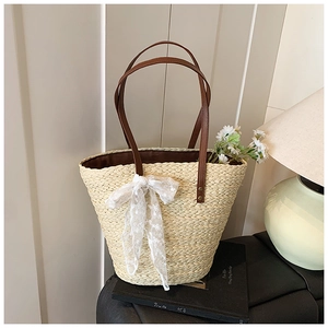 Detailansicht der Strohtasche mit weißer Spitzenschleife und braunen Ledergriffen