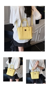 Detail view of yellow crossbody bucket bag showing saffiano texture and metal patch